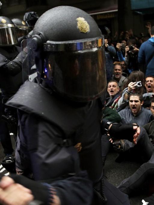 Ein spanischer Nationalpolizist geht mit seinem Schlagstock auf Befürworter des Katalonien-Referendums los, die sich auf die Straße gesetzt haben, am 01.10.2017 in Barcelona (Spanien).