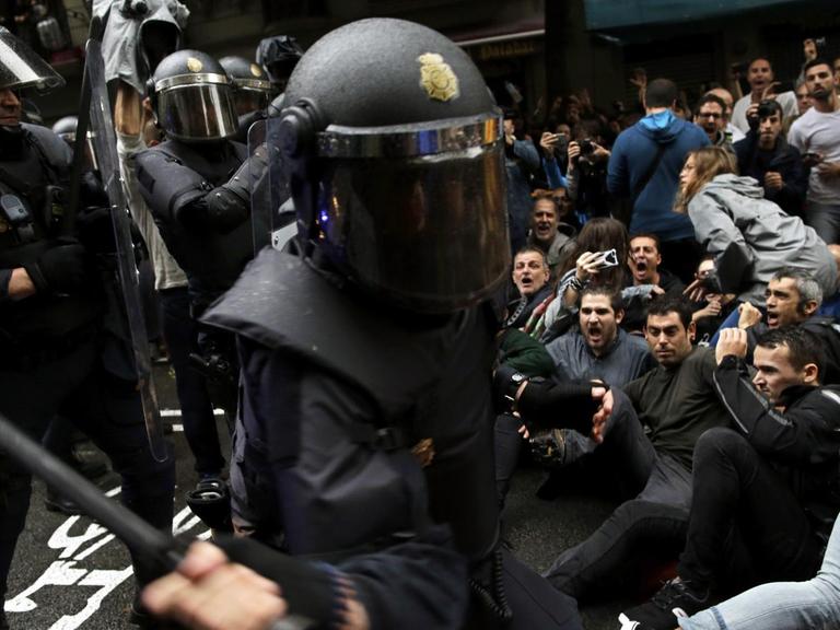 Ein spanischer Nationalpolizist geht mit seinem Schlagstock auf Befürworter des Katalonien-Referendums los, die sich auf die Straße gesetzt haben, am 01.10.2017 in Barcelona (Spanien).