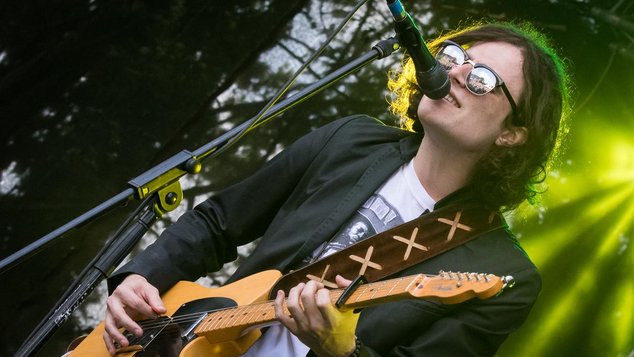 Ein Mann mit schwarzen Haaren und Sonnenbrille spielt Gitarre.