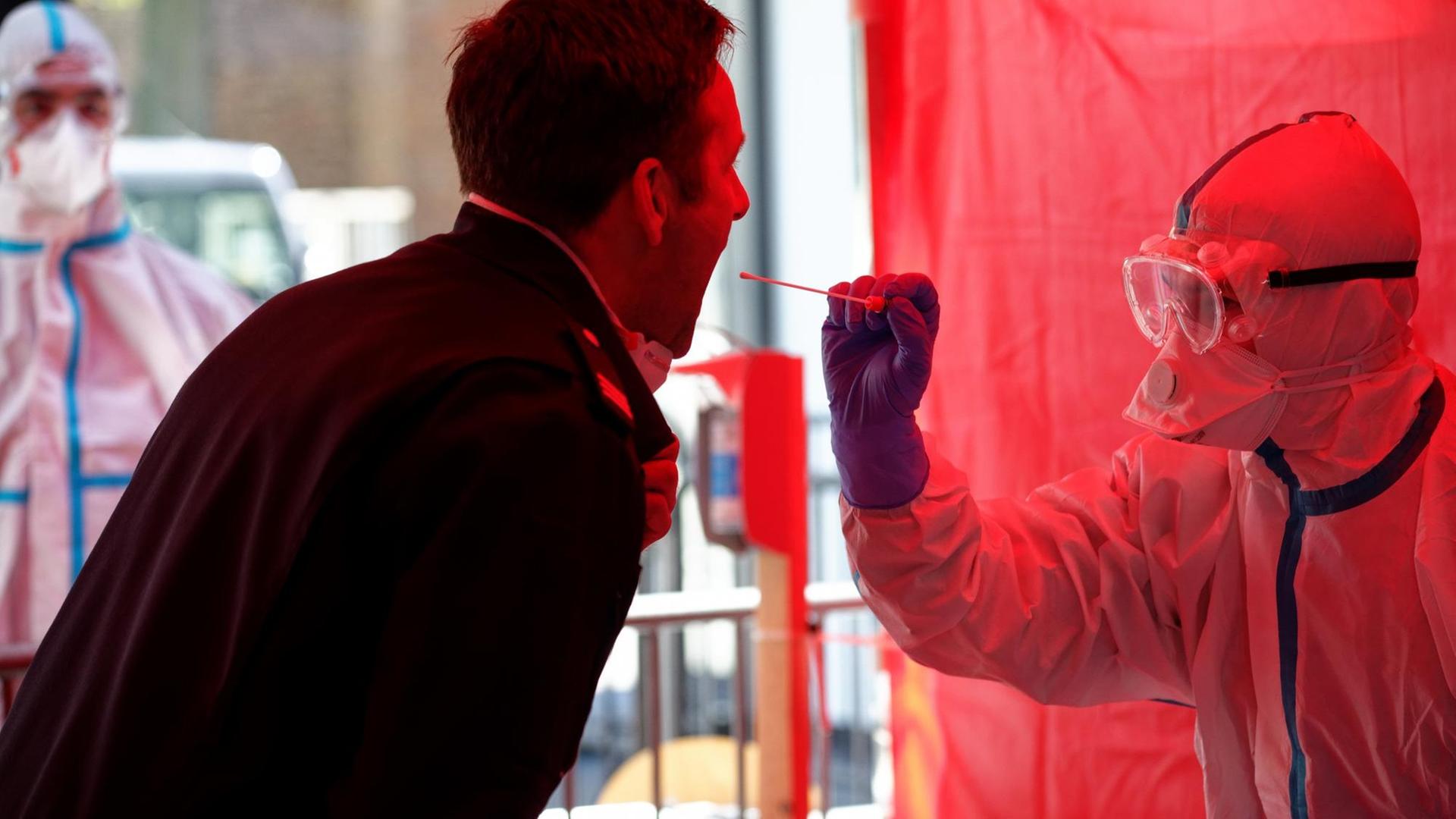Einem Mitarbeiter der Berufsfeuerwehr Köln wird im dritten Infektionsschutzzentrum der Stadt Köln mit einem Stäbchen ein Abstrich für einen Test auf den Coronavirus entnommen.