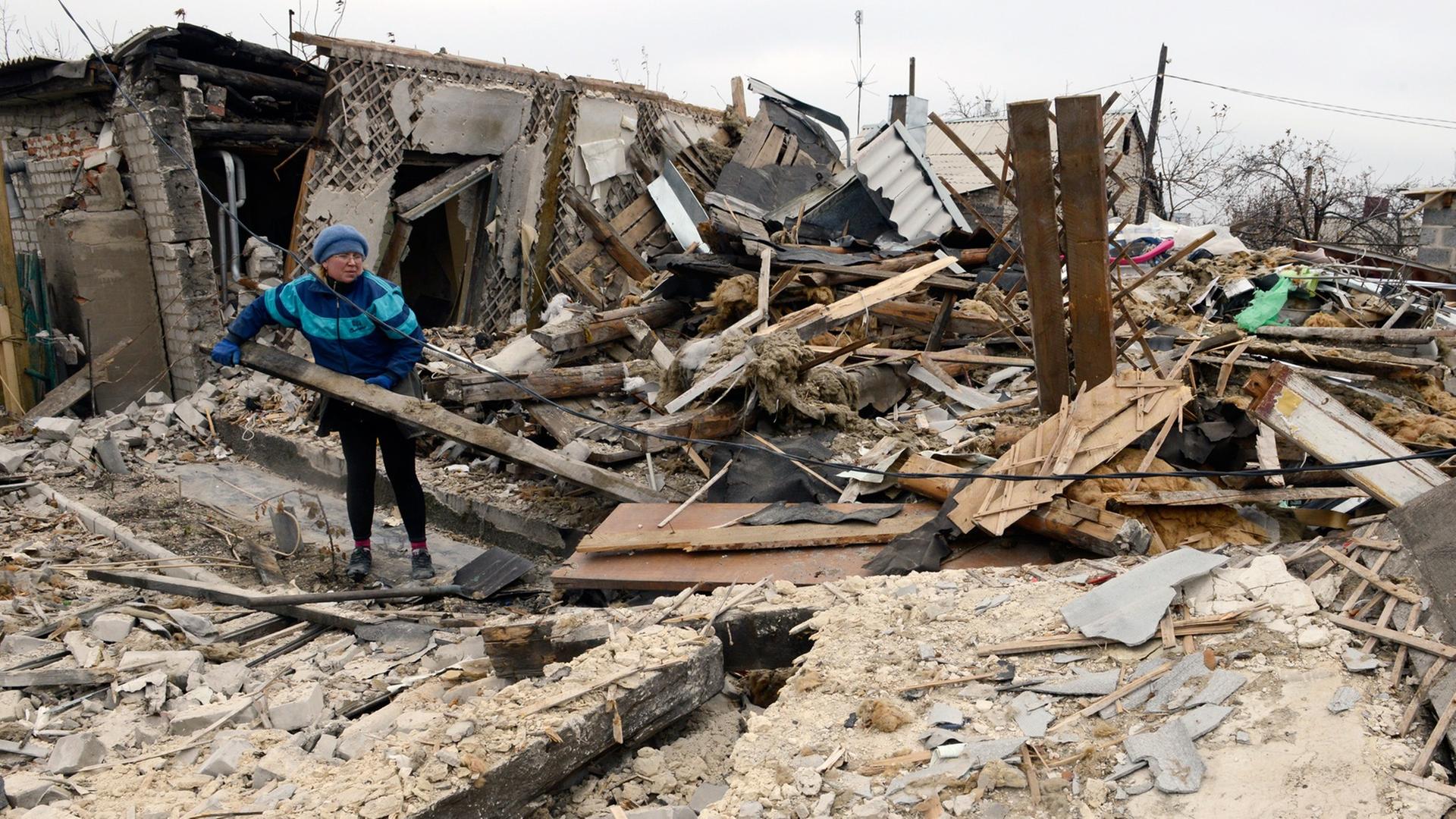Eine Frau steht in den Trümmern von ihrem Haus.