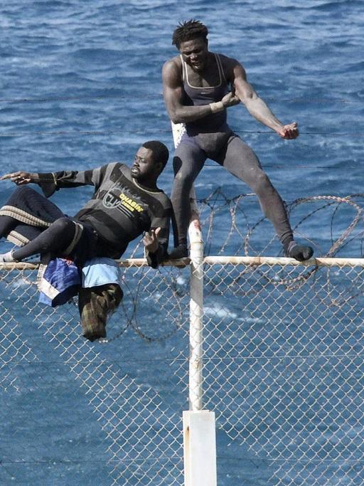 An der marokkanisch-spanischen Grenze in Ceuta (Sebta) im Norden Marokkos versuchen zwei Flüchtlinge, den Zaun zu überwinden. 3.2.2015.