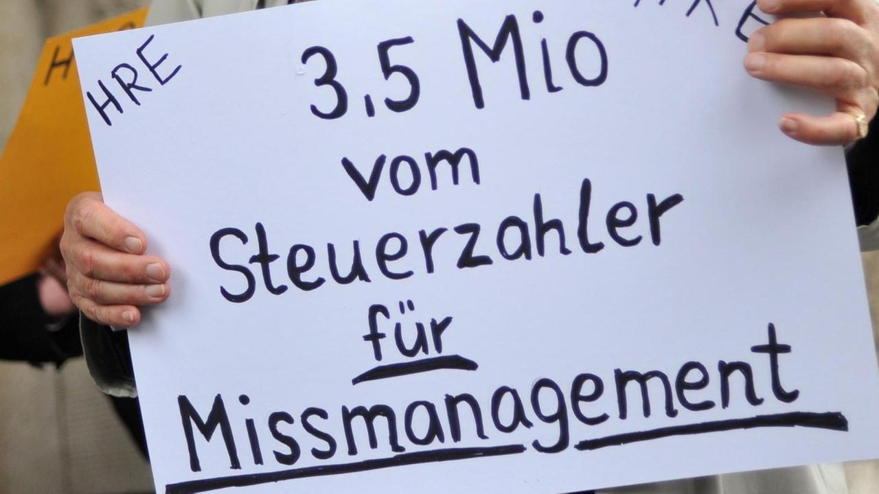 Ein demonstrierender Aktionär der Hypo Real Estate steht am Donnerstag (06.05.2010) vor dem Landgericht in München (Oberbayern) und hält ein Protestplakat in Händen.