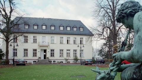 Gebäude der American Academy am Wannsee mit Gartenskulptur im Vordergrund.