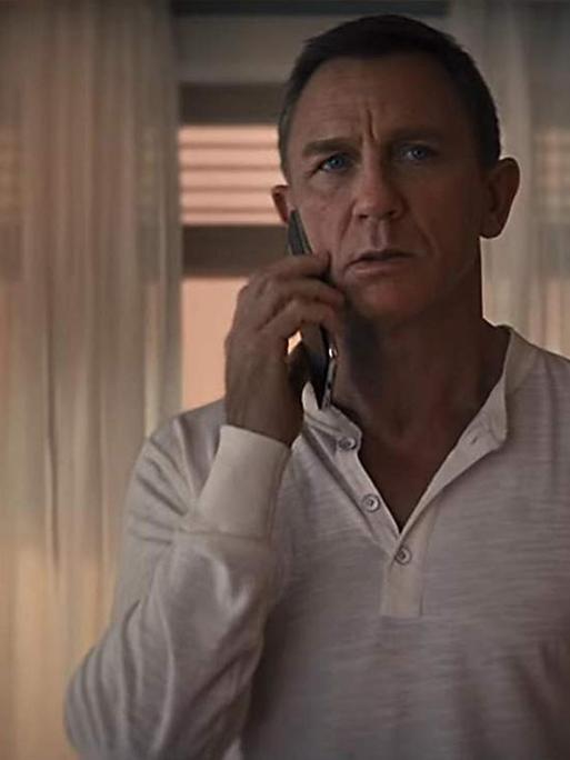 Schauspieler Daniel Craig alias James Bond telefoniert mit dem Smartphone.
