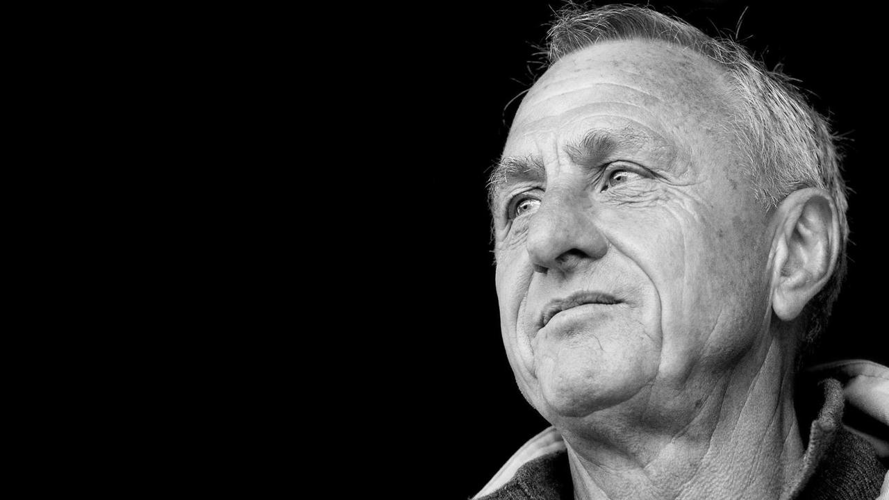 Das Bild zeigt Cruyff mit ernstem Blick von einem schwarzen Hintergrund.