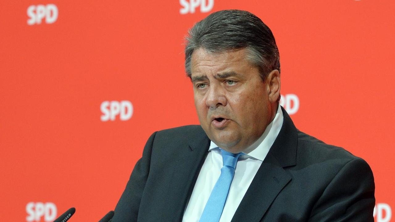 Der SPD-Vorsitzende Sigmar Gabriel spricht vor einer roten Wand mit SPD-Logos in ein Mikrofon.