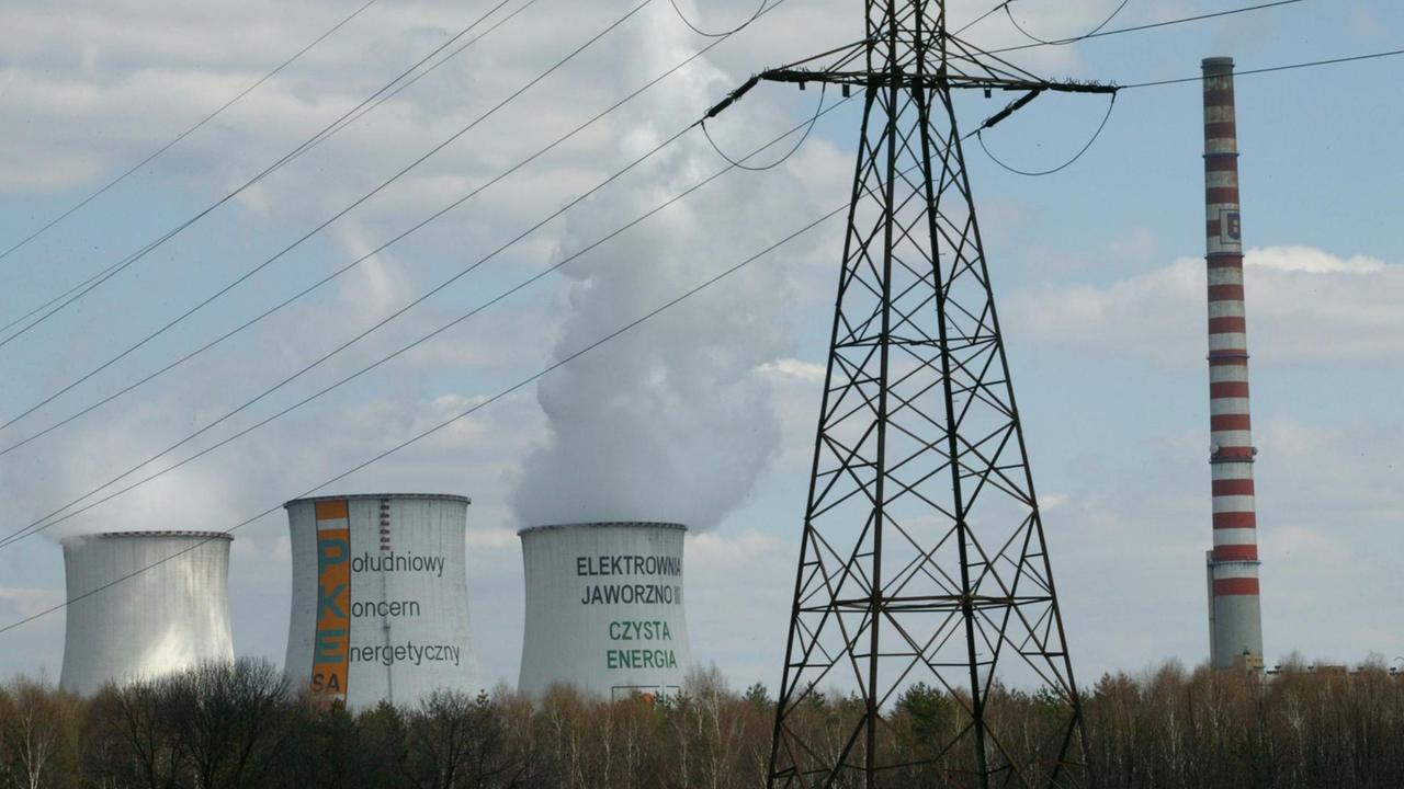 Rauchende Kühltürme des Kraftwerks des Energiekonzern Süd PKE in der Nähe von Kattowitz in einer Landschaft.