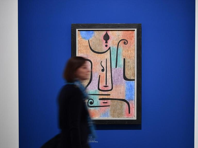 28.02.2018, Bayern, München: Eine Journalistin geht im Rahmen einer Pressevorstellung zur Ausstellung "Paul Klee. Konstruktion des Geheimnisses" an dem Werk "Erzengel" (1938) vorbei. Die Schau der Bayerischen Staatsgemäldesammlungen zeigt rund 150 Werke in der Pinakothek der Moderne. Die Ausstellung geht vom 01.03.2018 bis zum 10.06.2018.