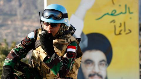 Ein Soldat der UNO-Truppen im Libanon (UNIFIL) hockt vor einem Poster des Hisbollah-Führers Nasrallah.