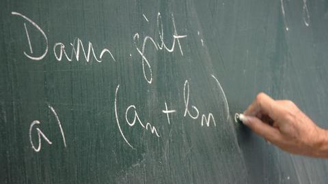 Jemand schreibt eine mathematische Formel auf eine Tafel