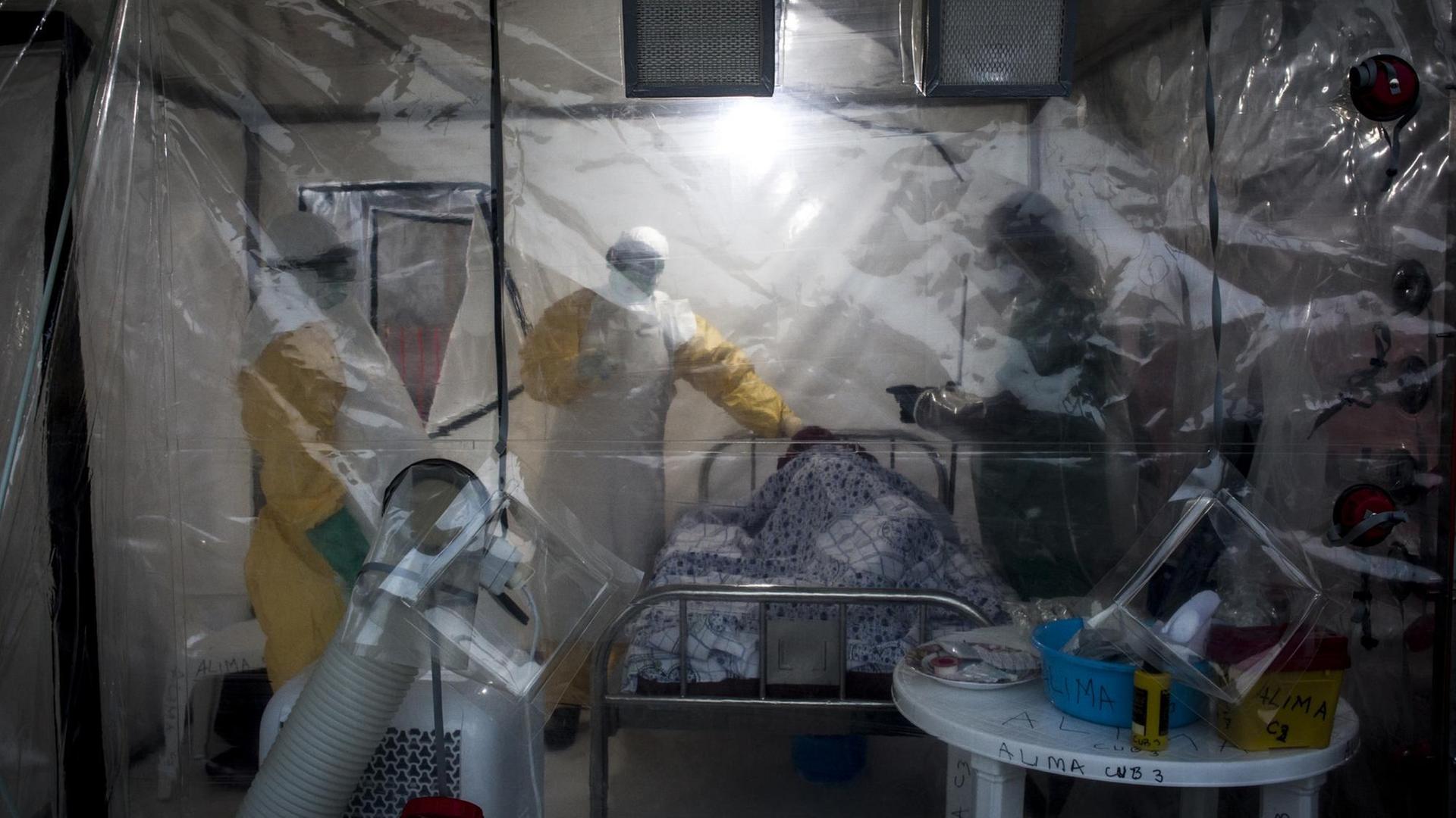 Das Bild zeigt mehrere Pfleger, die in Beni im Kongo einen Ebola-Patienten untersuchen. Dabei kommt erstmals auch ein Zelt mit einem speziellen Sicherheitssystem zum Einsatz.