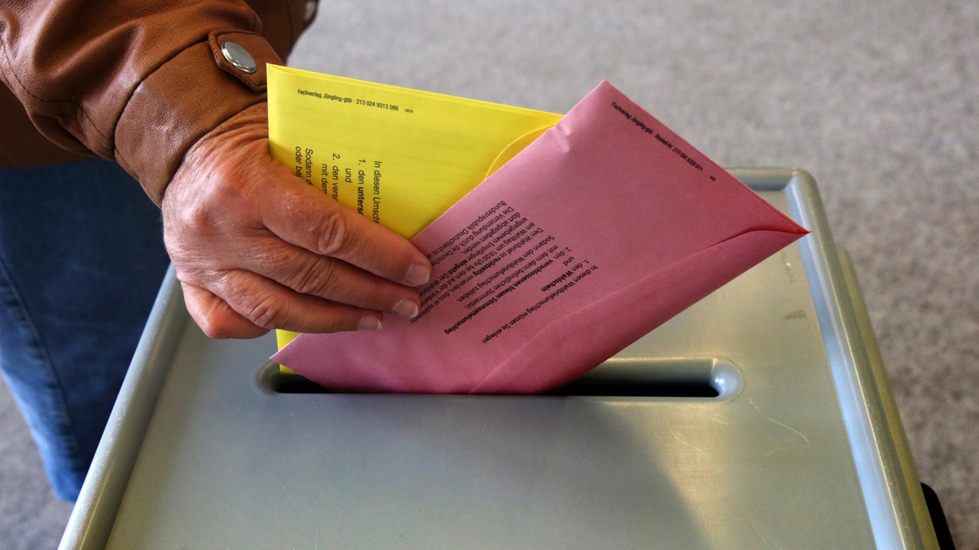 Ein Mann wirft Stimmzettel für die Europa- und Kommunalwahl in eine Urne