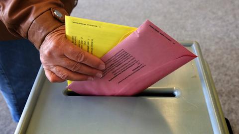 Ein Mann wirft Stimmzettel für die Europa- und Kommunalwahl in eine Urne
