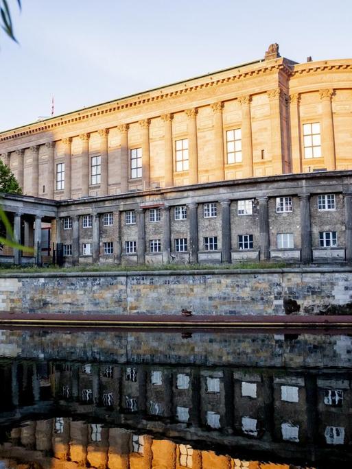 Die Alte Nationalgalerie spiegelt sich im Licht der aufgehenden Sonne in der Spree.