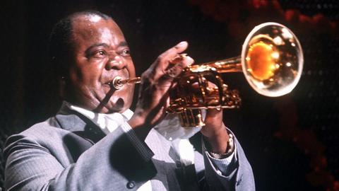 Der US-amerikanische Jazz-Trompeter Louis Armstrong, aufgenommen während eines Auftritts in der Jahrhunderthalle Höchst im Jahr 1965. Amerika feiert am 4.7.2000 den 100. Geburtstag des legendären Jazzmusikers. Dabei wissen die Fans von «Satchmo», dass die Feiern eigentlich um 13 Monate zu früh kommen. «The King of Jazz» wurde in Wirklichkeit am 4. August 1901 geboren, hatte aber eigenmächtig seinen Geburtstag auf den Unabhängigkeitstag verschoben. Das größte Memorial-Konzert für Armstrong findet nach einer internationalen Flottenparade zum Unabhängigkeitstag auf dem Hudson-River in New York statt.