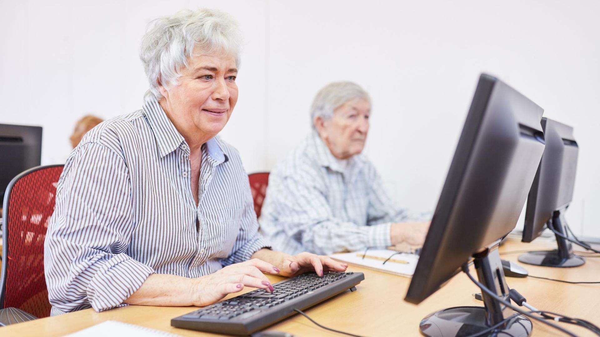 Eine Seniorin in einem Altersheim sitzt bei einer Computerschulung am PC.