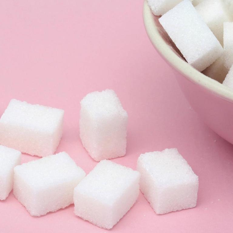 Mehrere Stücke Würfelzucker liegen auf dem Tisch und in einem Schälchen.