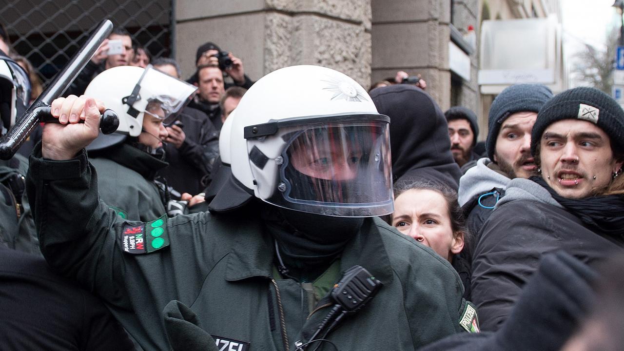 Mit dem Schlagstock geht ein Polizist am 14.03.2015 in Wuppertal gegen Demonstranten vor.
