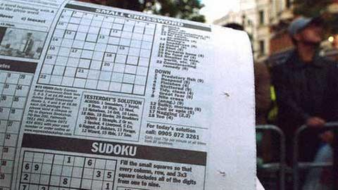 Ein Zeitungsleser löst ein Sudoku-Rätsel.
