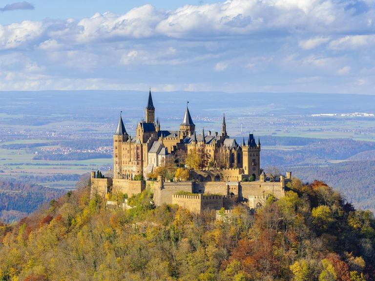 Das Bild zeigt die Burg Hohenzollern auf der schwäbischen Alb im Herbst vor einem Himmel mit vielen Wolken.