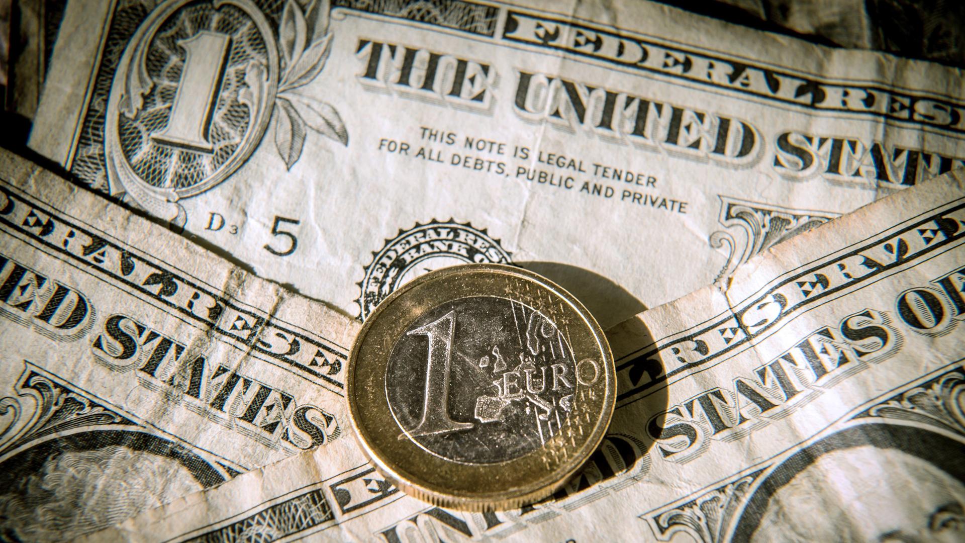 Euromünze auf Dollarscheinen