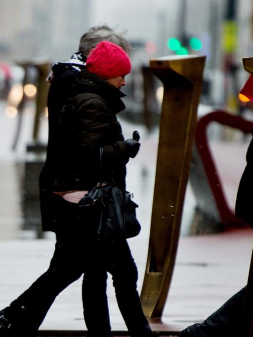 Passanten schützen sich am 10.12.2014 am Potsdamer Platz in Berlin mit Schirmen vor dem Regen.