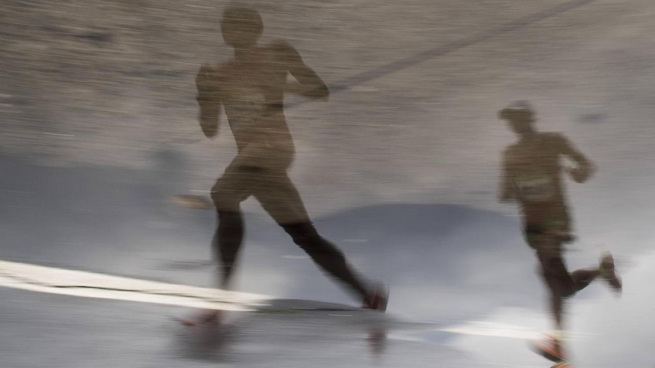 Marathon-Läufer bei den Olympischen Spielen in Rio de Janeiro spiegeln sich in einer Pfütze.