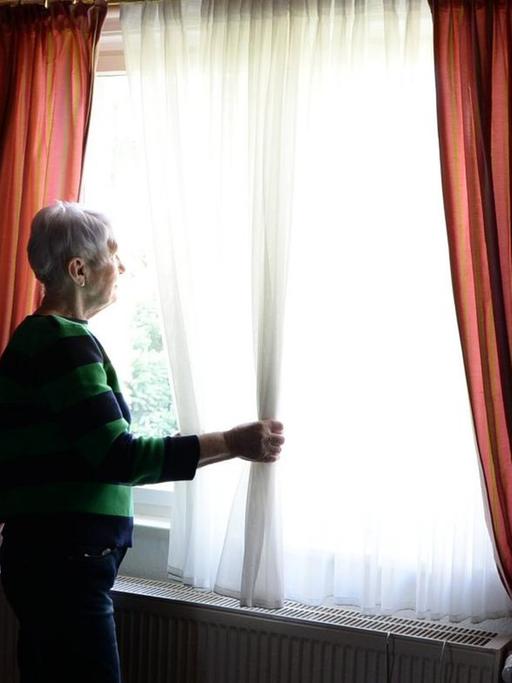 Eine ältere Frau schaut aus dem Fenster (gestellte Szene)