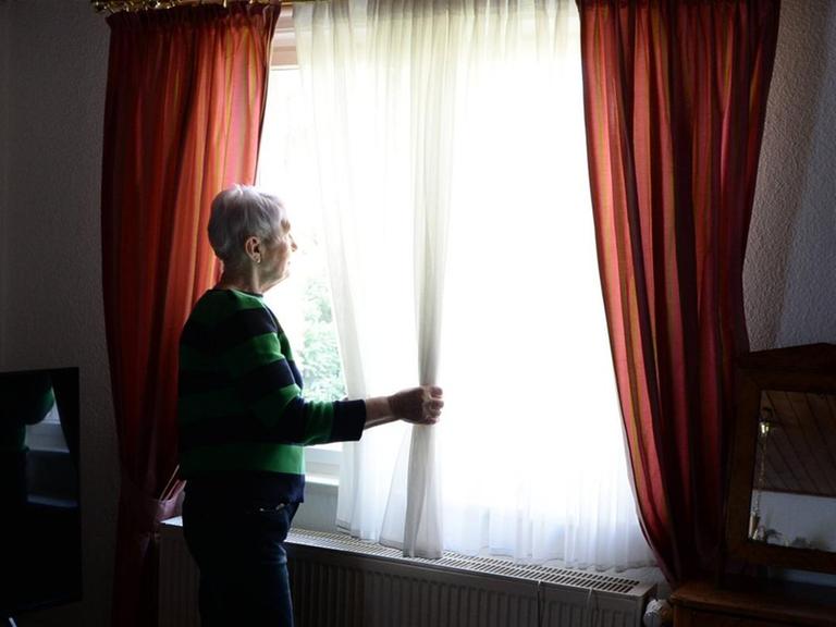 Eine ältere Frau schaut aus dem Fenster (gestellte Szene)