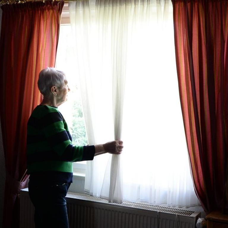Eine ältere Frau schaut aus dem Fenster (gestellte Szene)