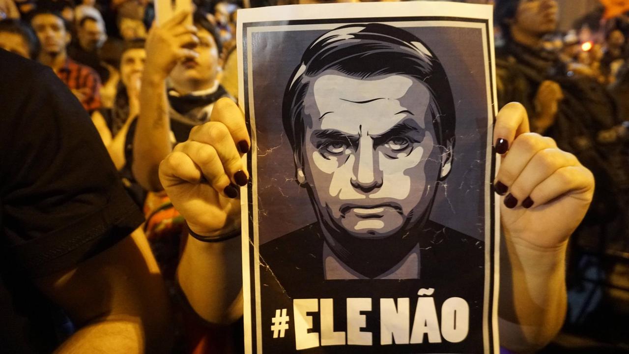 Auf einem Protestplakat ist ein Bild von Jair Bolsonaro zu sehen.
