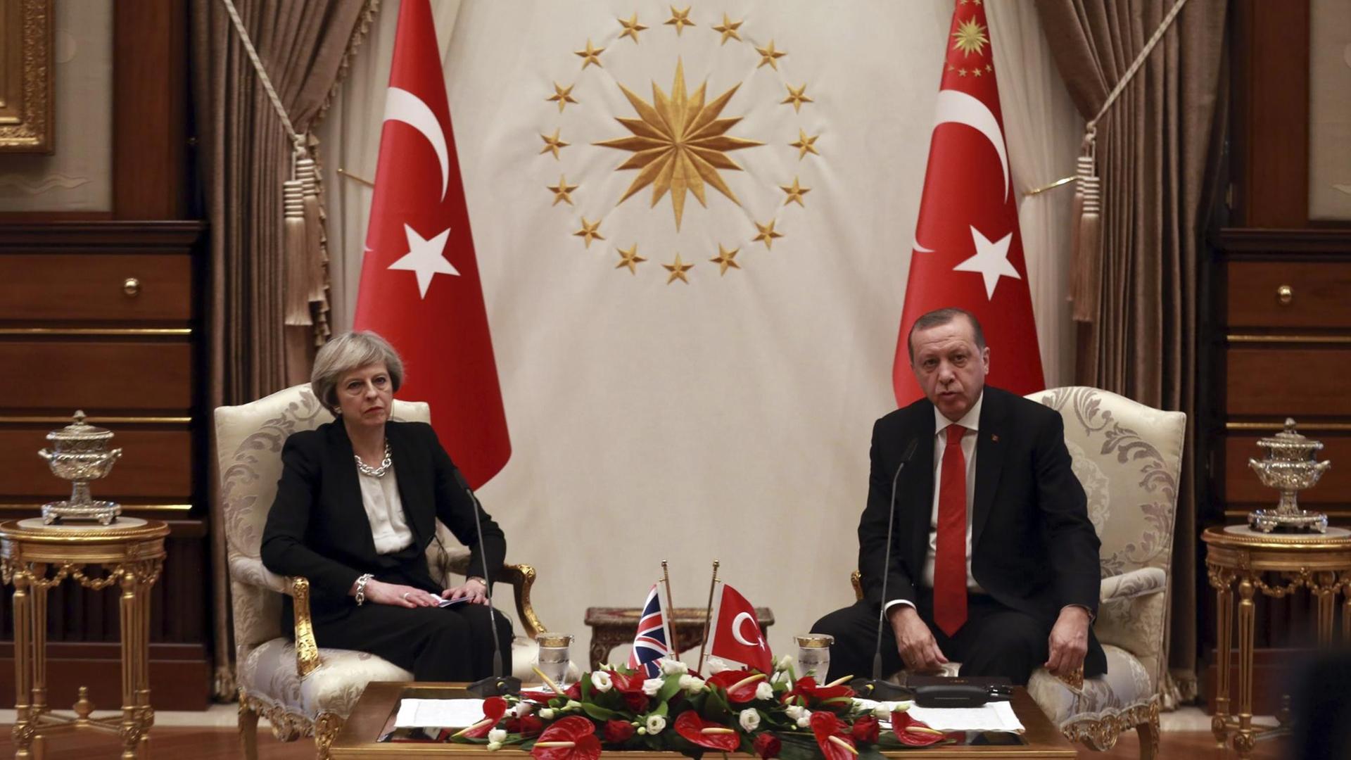 Theresa May und Recep Tayyip Erdogan sitzen in Stühlen vor zwei türkischen Flaggen
