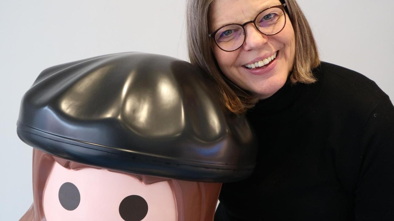 Das Bild zeigt Yvonne Coulin, die eine übergroße Martin Luther-Playmobilfigur umarmt. 