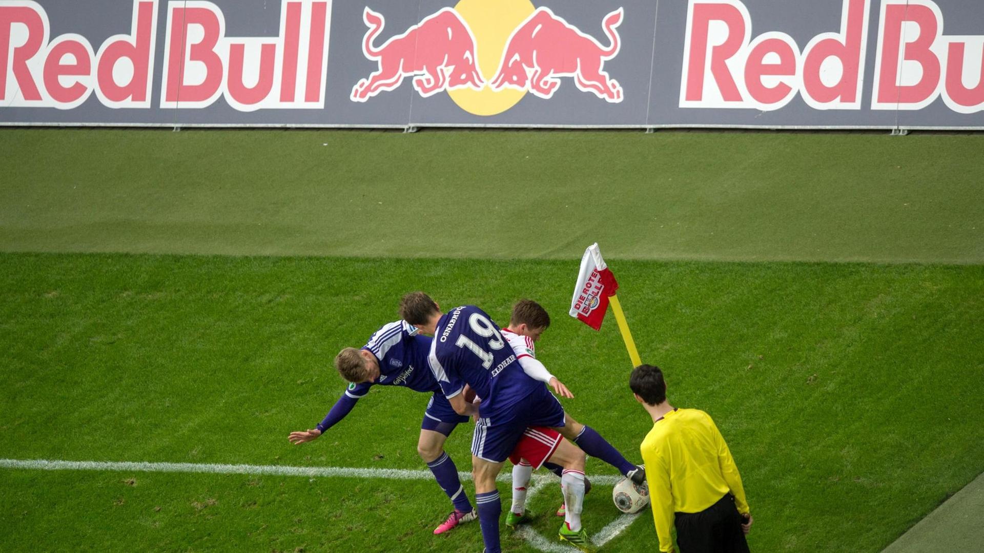 Leipzigs Dominik Kaiser (weiss) kämpft mit Osnabrücks Michael Blum (l) und Nicolas Feldhahn vor einer Red Bull Werbebande um den Ball.