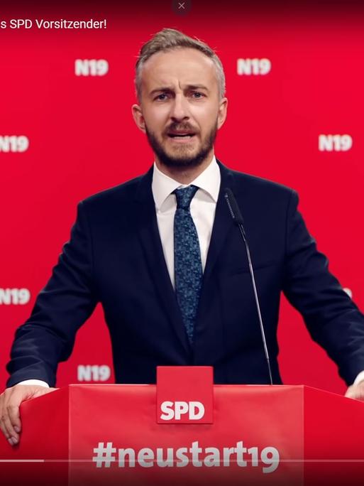 Der Screenshot zeigt den TV-Moderator und Satiriker Jan Böhmermann in einem Youtube-Video vor rotem Hintergrund an einem Rednerpult mit SPD-Logo. (Copyright Jan Böhmermann)