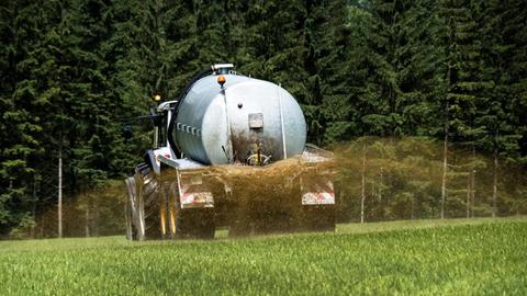 Ein Bauer bringt mit einem Traktor Gülle auf ein Feld.
