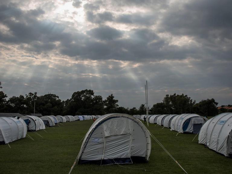 In einem Rugby Stadion stehen in ordentlichen Reihen weiße Zelte für circa 400 Personen.