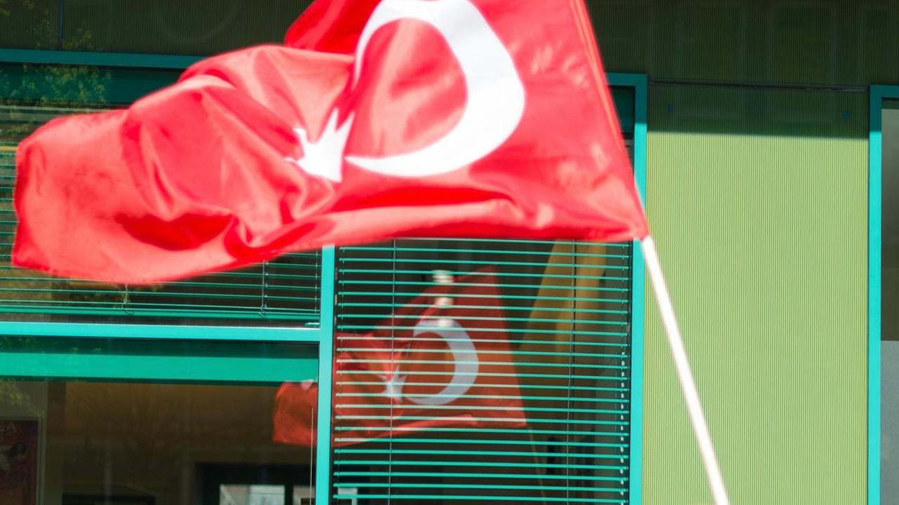 Ein Mann in osmanischer Tracht trägt eine türkische Fahne.