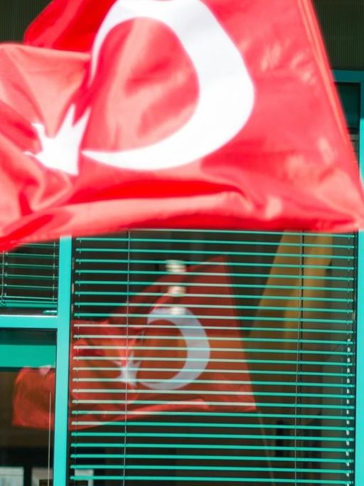 Ein Mann in osmanischer Tracht trägt eine türkische Fahne.