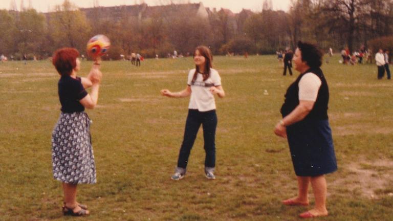 Drei Frauen werfen sich im Park einen Ball zu.