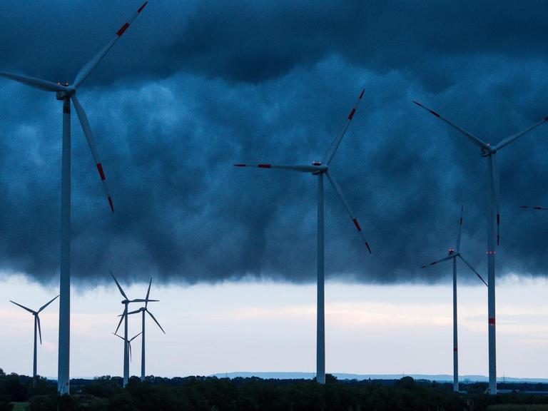 Windenergieanlagen sind am 04.09.2016 unter dunklen Gewitterwolken über dem Landkreis Oder-Spree nahe Sieversdorf (Brandenburg) zu sehen.