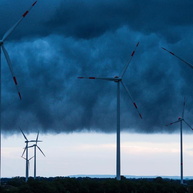 Windenergieanlagen sind am 04.09.2016 unter dunklen Gewitterwolken über dem Landkreis Oder-Spree nahe Sieversdorf (Brandenburg) zu sehen.