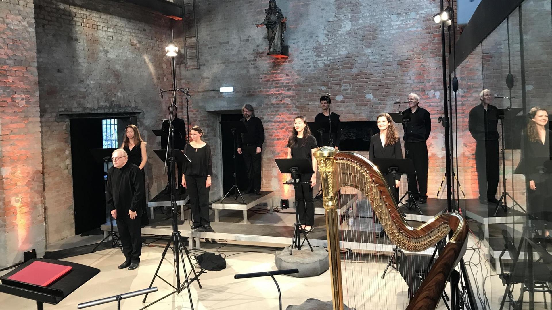 In einer Kirche steht eine Gruppe von schwarz gekleideten Musikerinnen und Musikern zum Konzert zusammen. Im Vordergrund ist eine Harfe zu sehen.