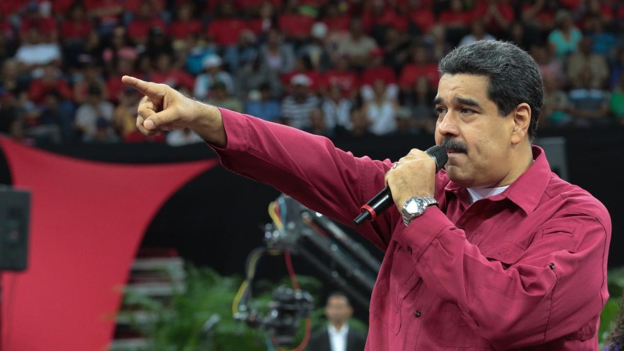 Das Bild zeigt den venezolanischen Präsidenten Nicolas Maduro am 27.06.2017 vor Anhängern in Caracas. Er trägt ein rotes Hemd und spricht in ein Mikrofon in seiner linken Hand. Mit dem rechten Arm zeigt er nach vorne.