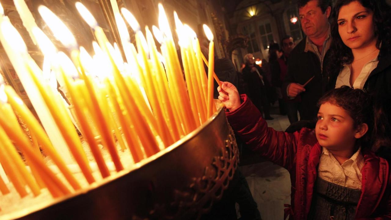 Christen bei einer Griechisch-orthodoxen Oster-Zeremonie in Istanbul zünden Kerzen an. Ein Mädchen hält ihre Kerze gerade ins Feuer.