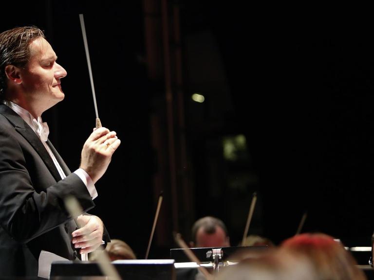 Der Dirigent Stefan Klingele steht vor einem Orchester und dirigiert