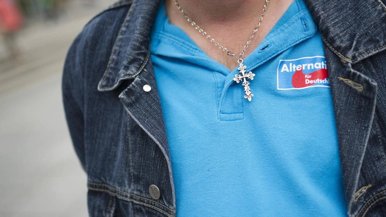 Ein Besucher einer Wahlveranstaltung der Partei Alternative für Deutschland (AfD) trägt eine Kette mit einem Kreuz und ein blaues T-Shirt mit dem Logo der AfD.