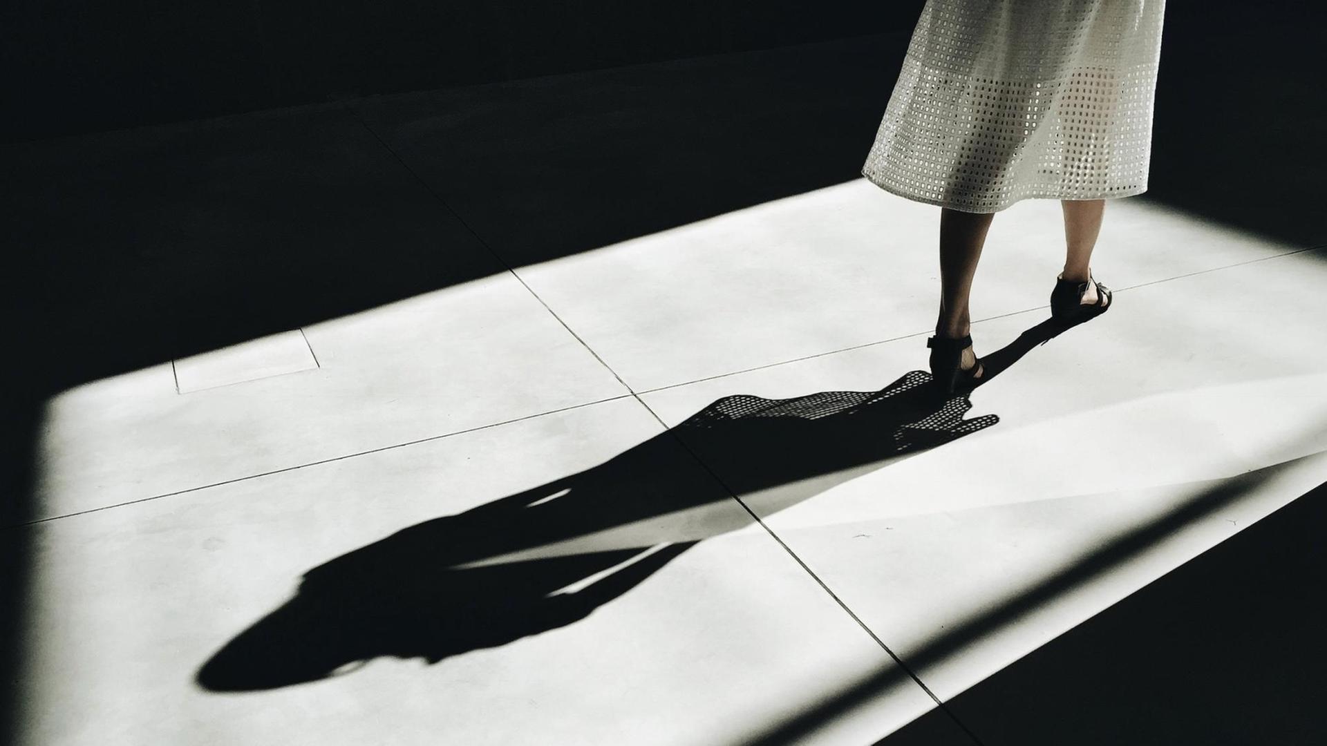 Der Schatten einer Frau zeichnet sich auf dem Boden ab.