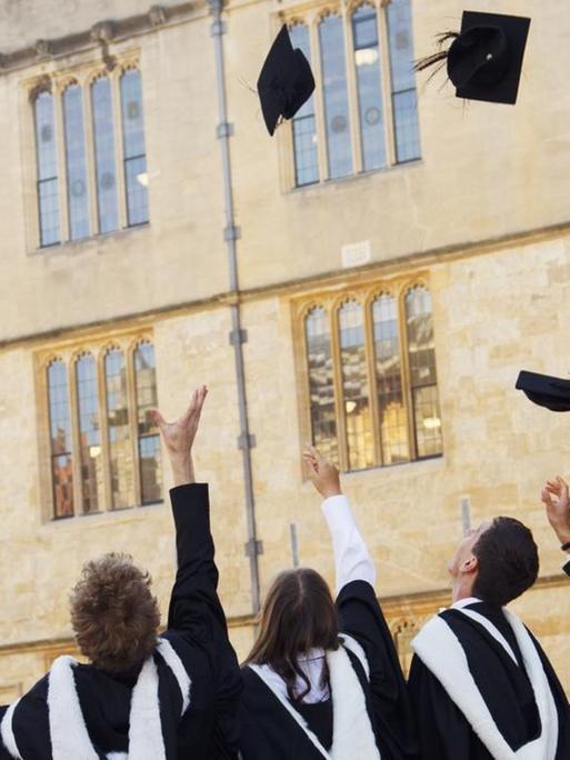 Bachelors der University of Oxford in Grossbritannien werfen ihre Hüte in die Luft vor dem Universitätsgebäude.